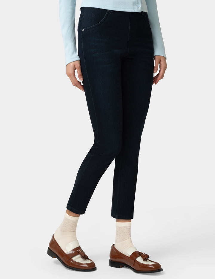 Person wearing black jeans with a light blue shirt and brown shoes on a white background