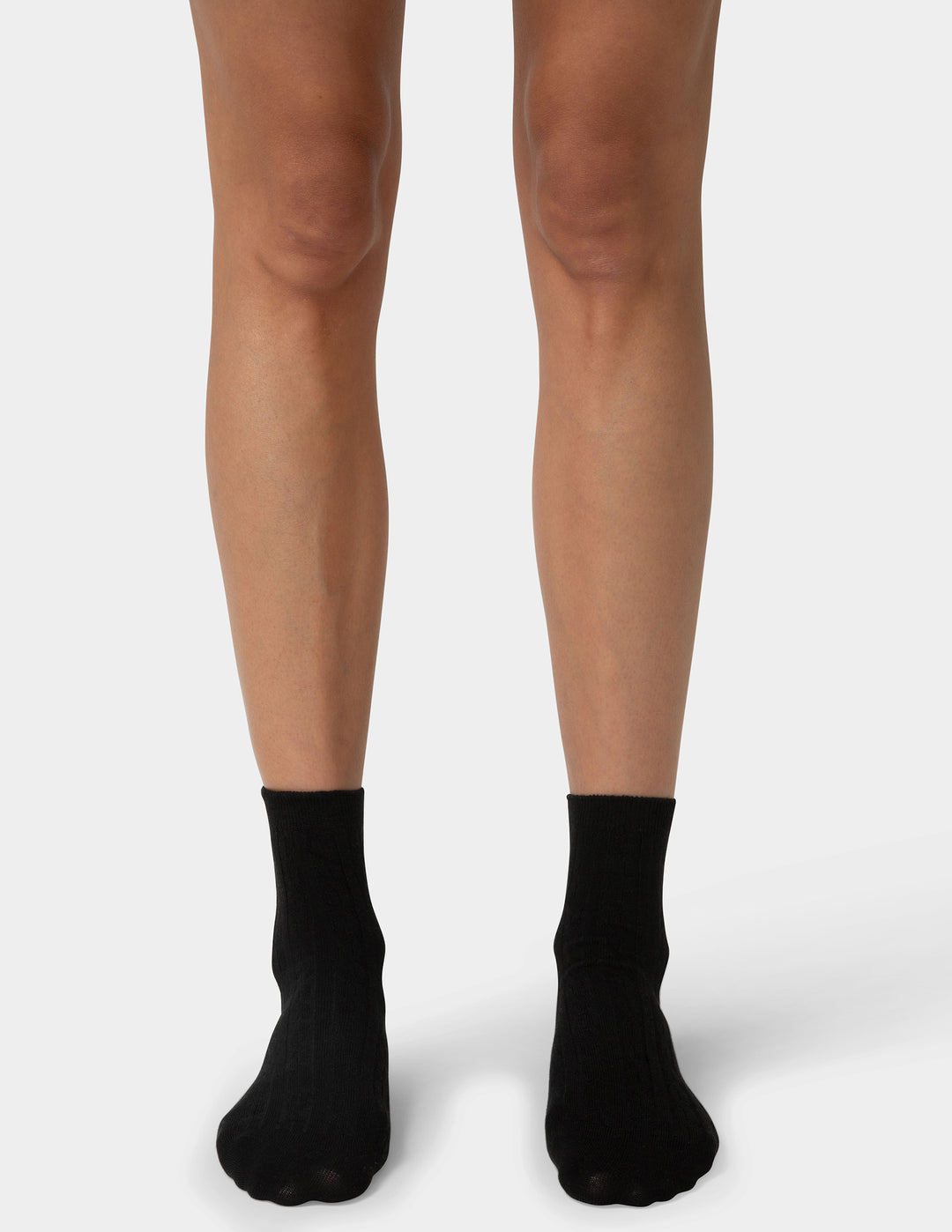 Black socks worn with beige tights on a white background