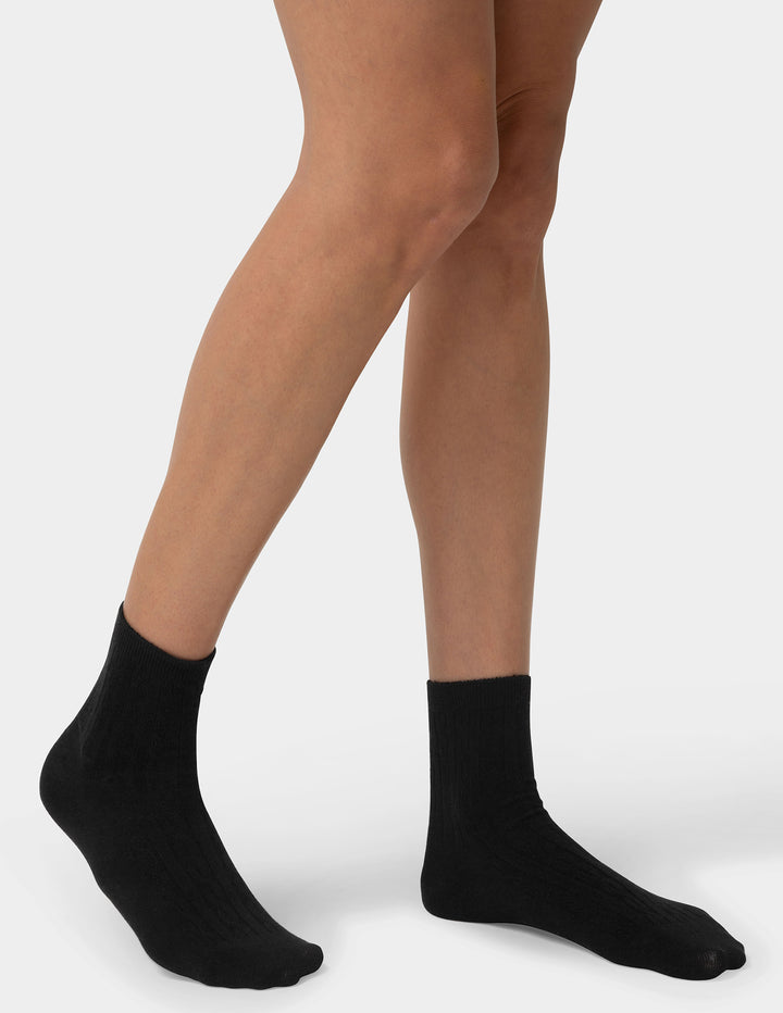 Person wearing black socks on a plain background