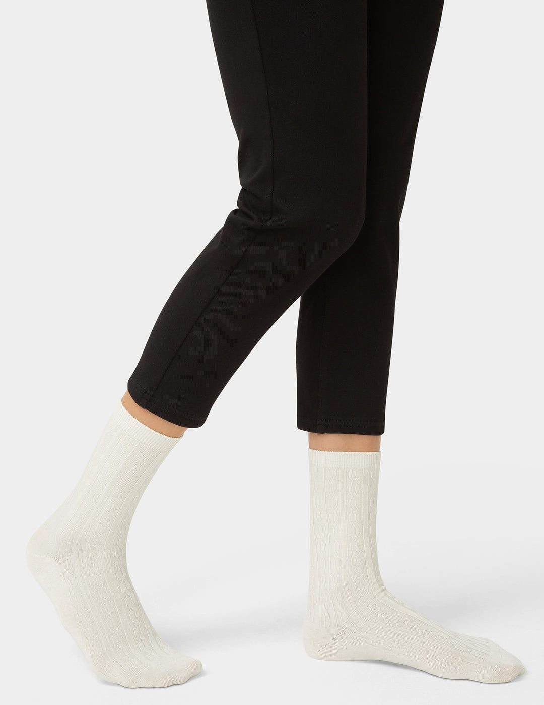 Person wearing black leggings and white socks on a white background