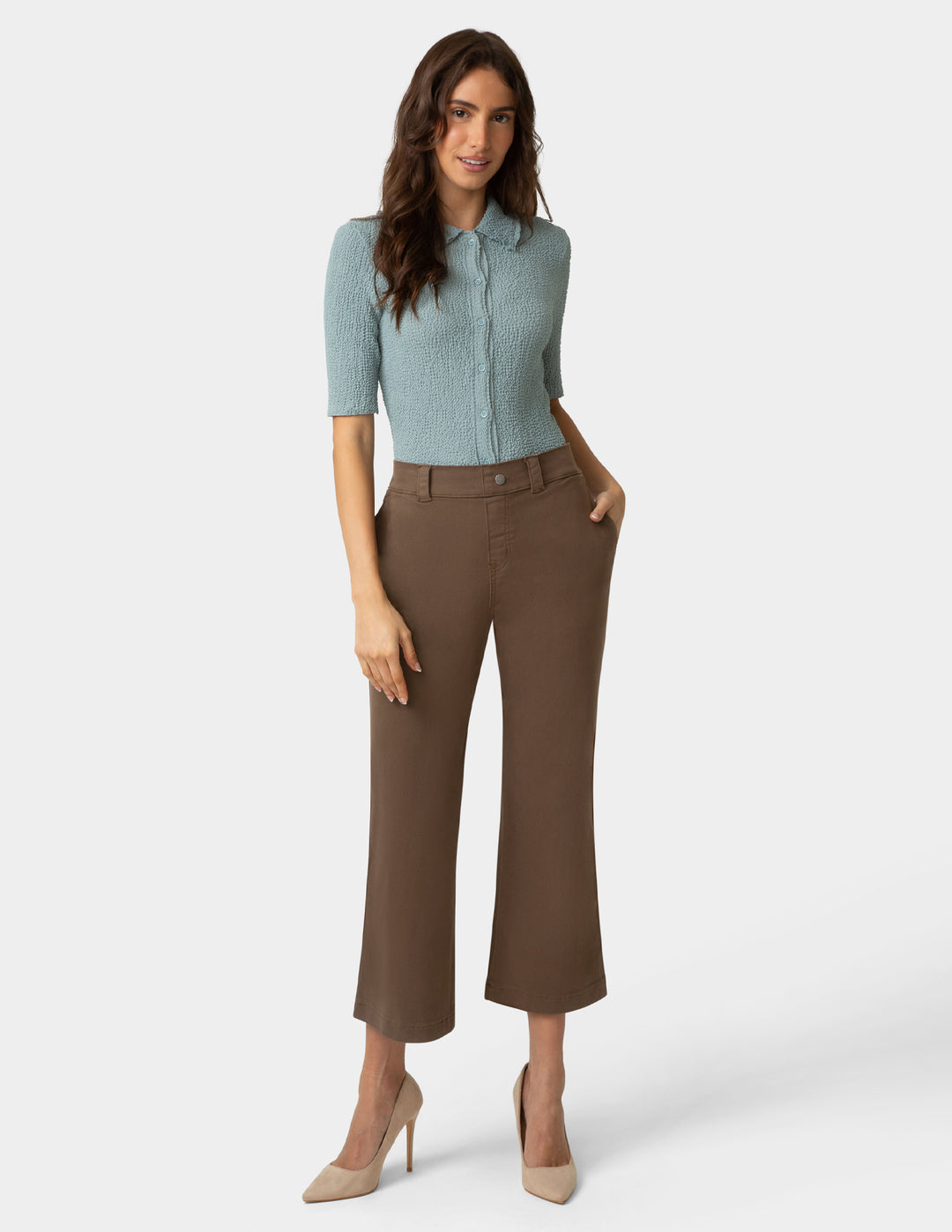 Woman wearing a light blue shirt and brown pants on a white background