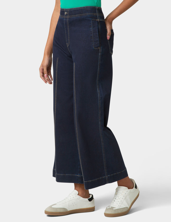 Person wearing dark blue wide-leg jeans with a white background