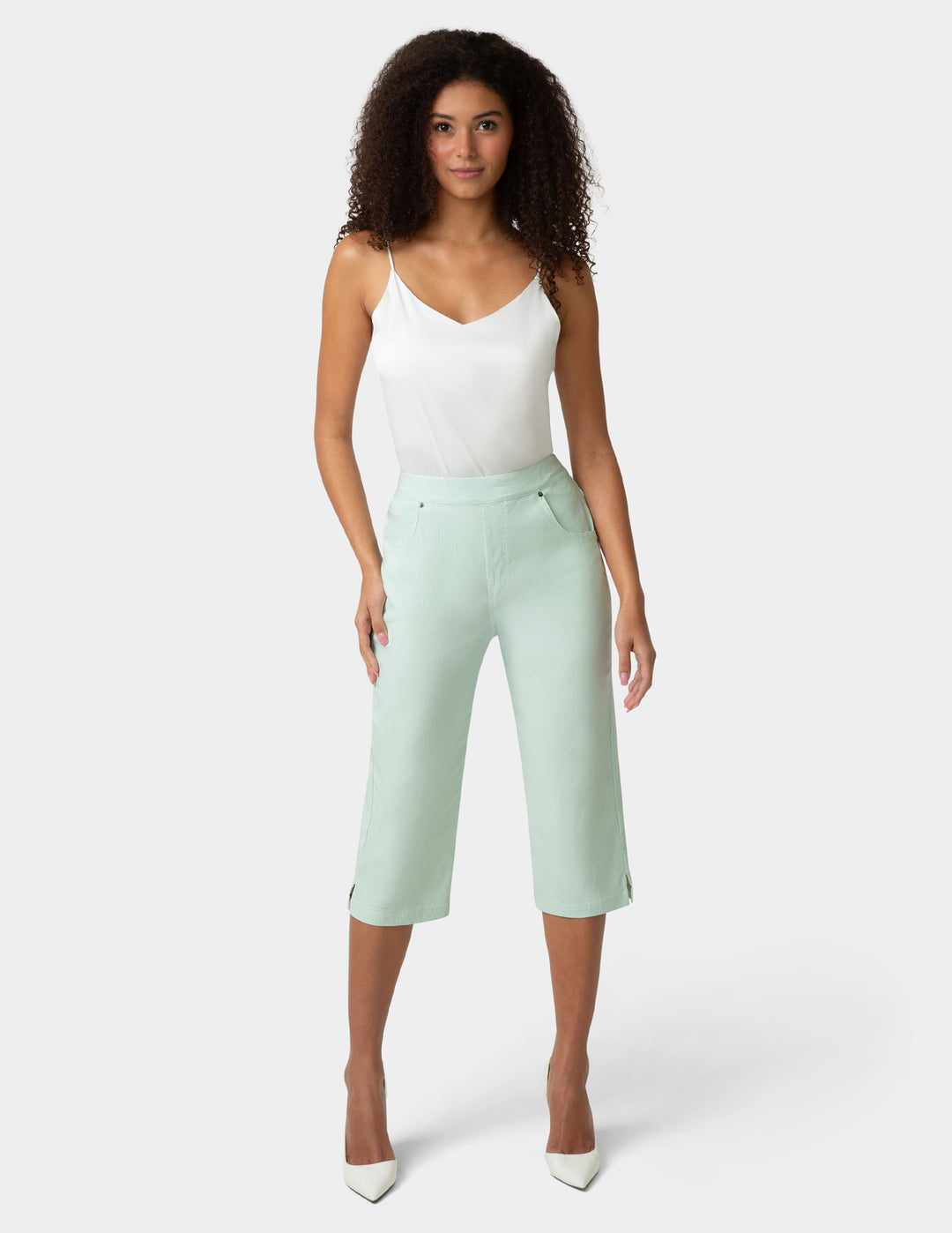 Woman wearing a white top and light green capri pants on a white background