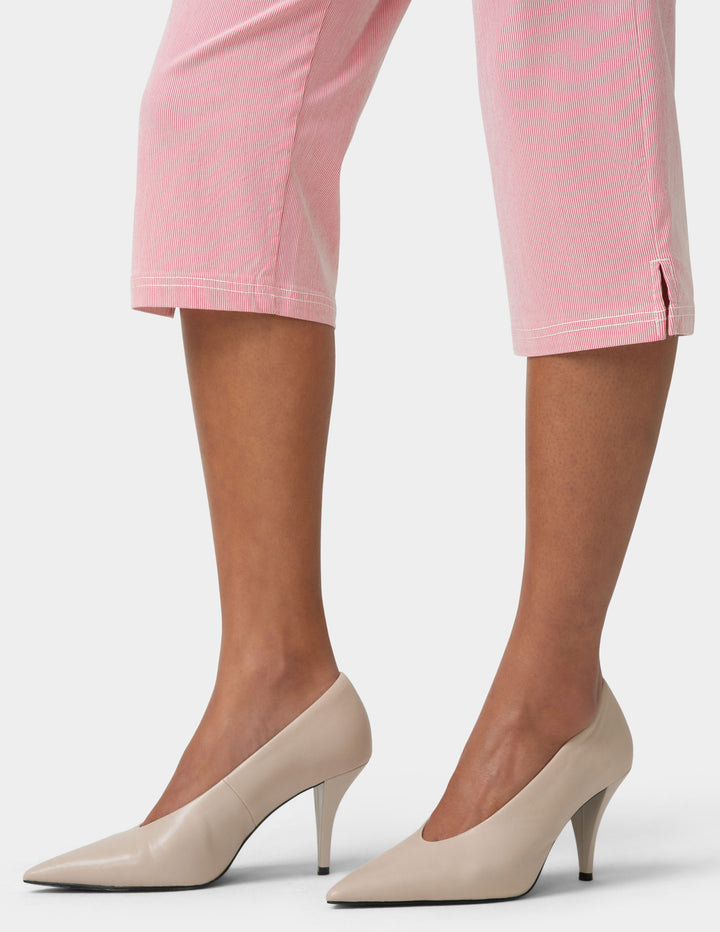 Beige high heels worn with pink pants on a light gray background