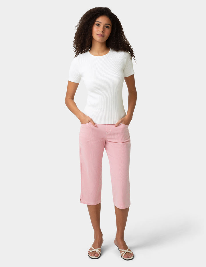Woman wearing a white t-shirt and pink capri pants on a white background
