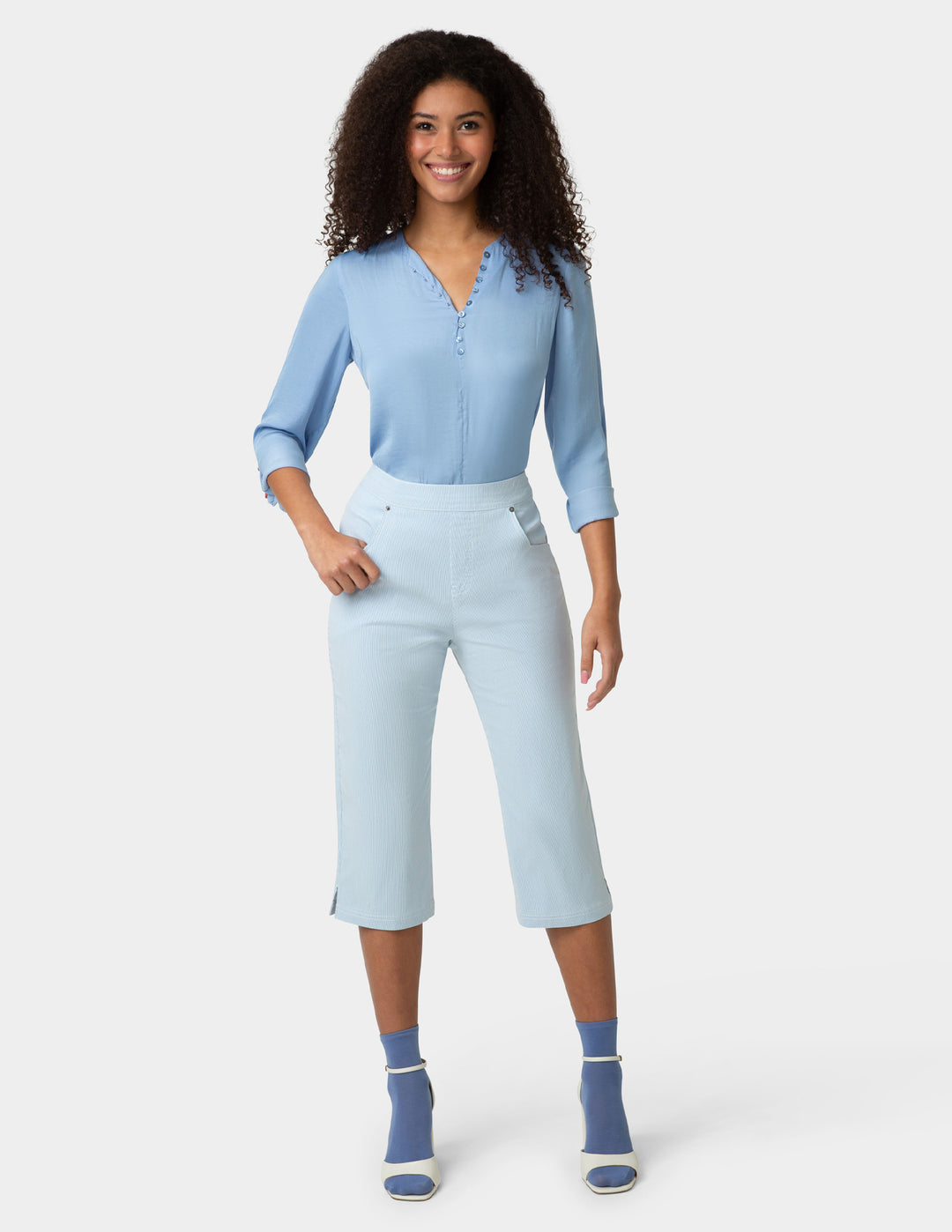 Woman wearing a light blue outfit with matching shoes on a white background