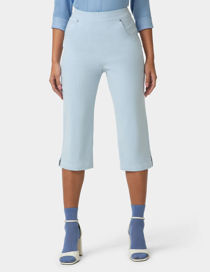 Person wearing light blue capri pants with a white background
