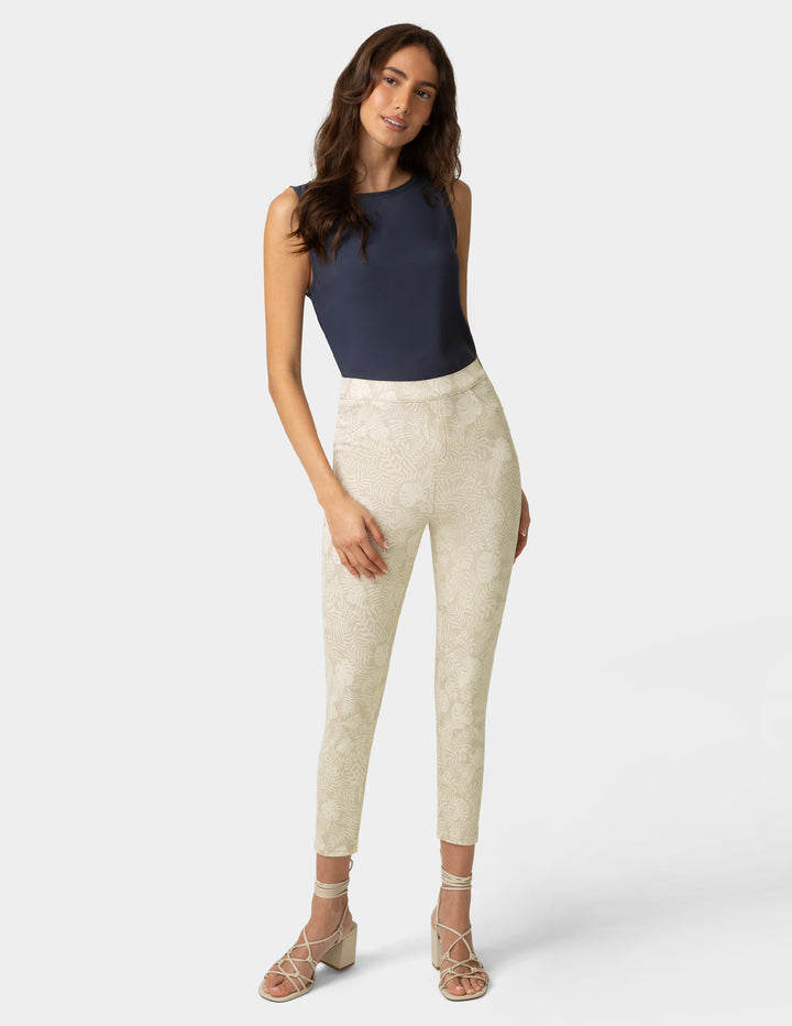 Woman wearing a navy top and beige patterned pants on a white background