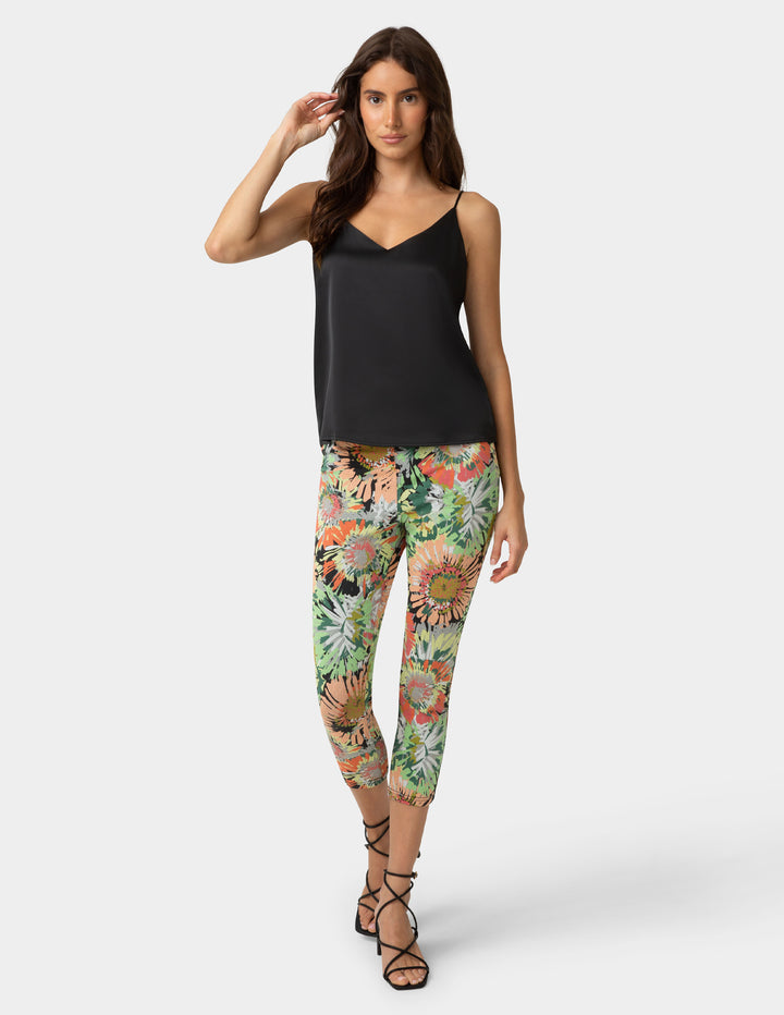 Woman wearing a black top and colorful floral pants on a white background