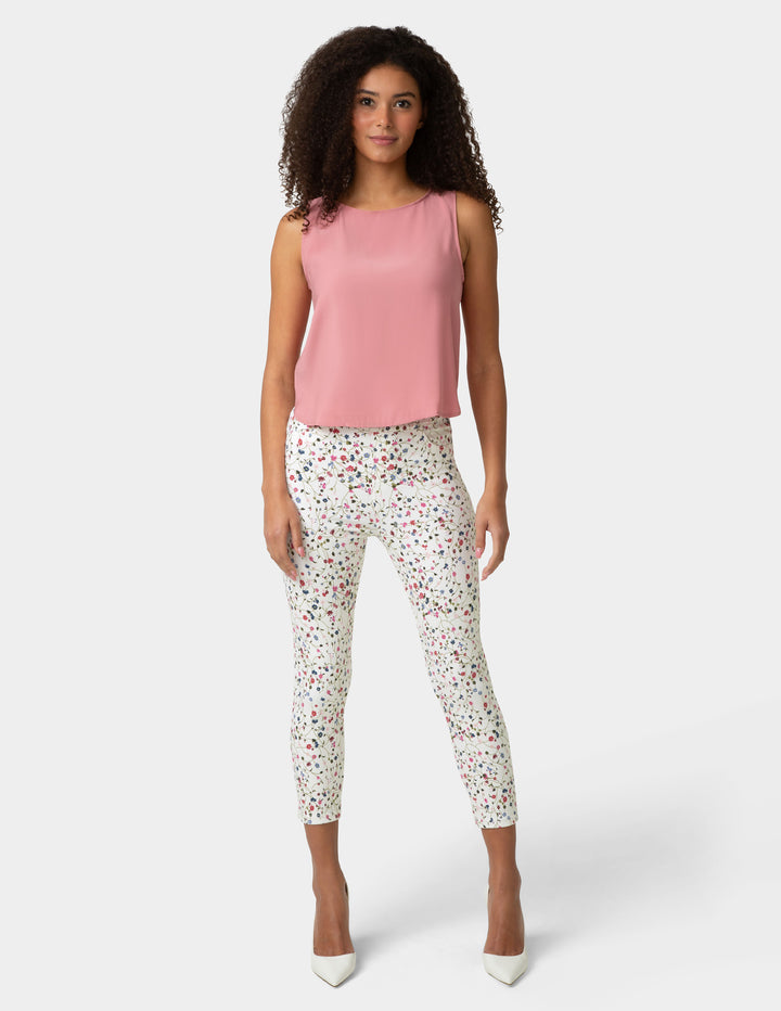 Woman wearing a pink sleeveless top and patterned pants on a white background