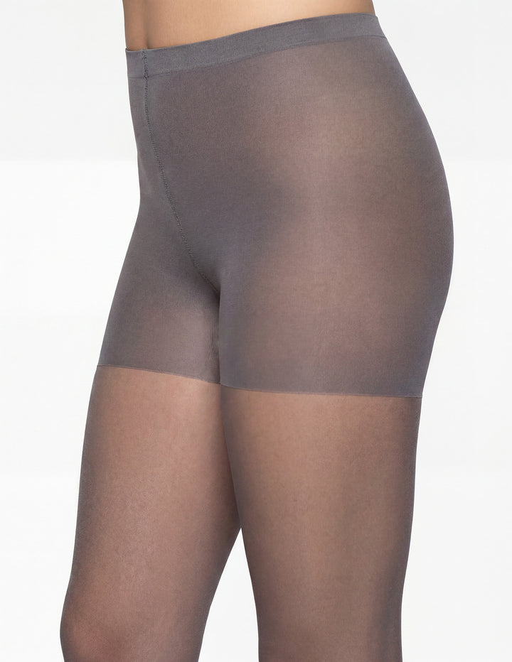 A close-up side view of a model wearing sheer gray hosiery against a plain white background.