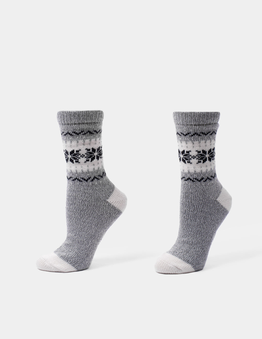 A pair of gray knit socks with a black and white Fair Isle pattern around the calf, shown on a clean white background.
