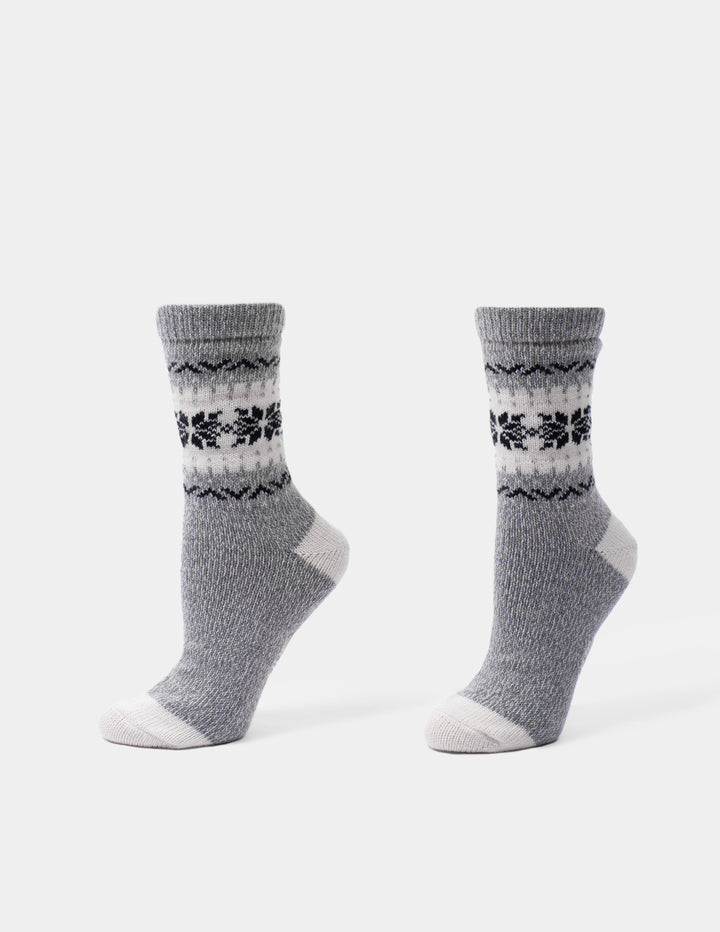 A pair of gray knit socks with a black and white Fair Isle pattern around the calf, shown on a clean white background.