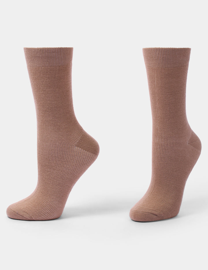 A pair of ribbed crew socks in a tan color, shown from the side on a light gray background.