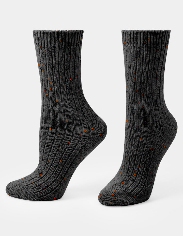 A pair of dark charcoal gray ribbed crew socks with small orange speckles, shown on a light gray background.