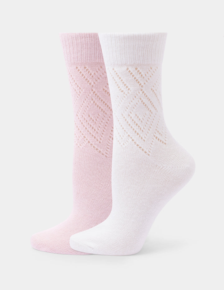Two crew socks, one light pink and one white, featuring a textured openwork diamond pattern on the upper half and ribbed cuffs, displayed against a light gray background.