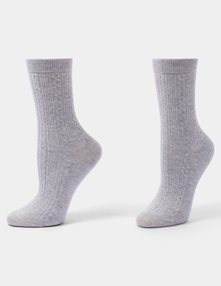 A pair of light gray cable-knit crew socks displayed on invisible forms against a clean white background.