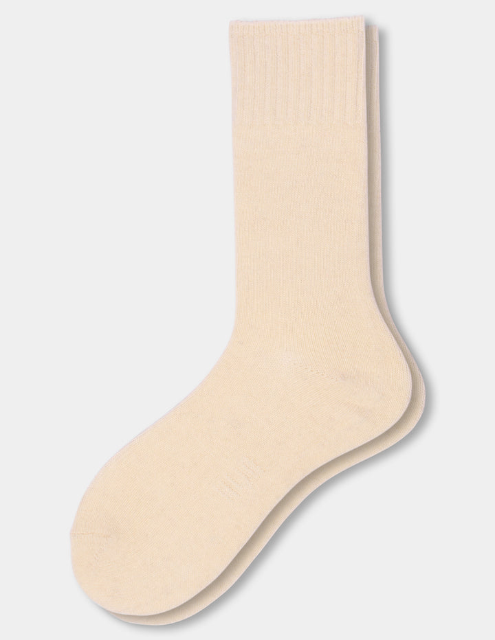 A pair of light beige crew socks stacked together on a light gray background.
