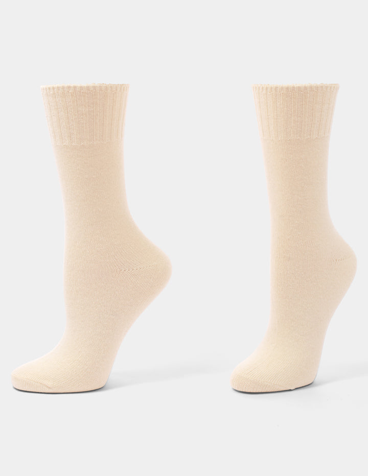 A pair of light beige crew socks on a light gray background.