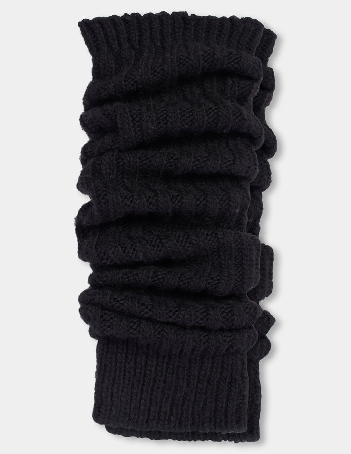 Ribbed black leg warmers laying flat, photographed against a light gray background.