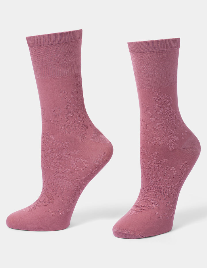 A pair of dusty pink crew socks with an embossed floral pattern on the foot, displayed against a light gray background.