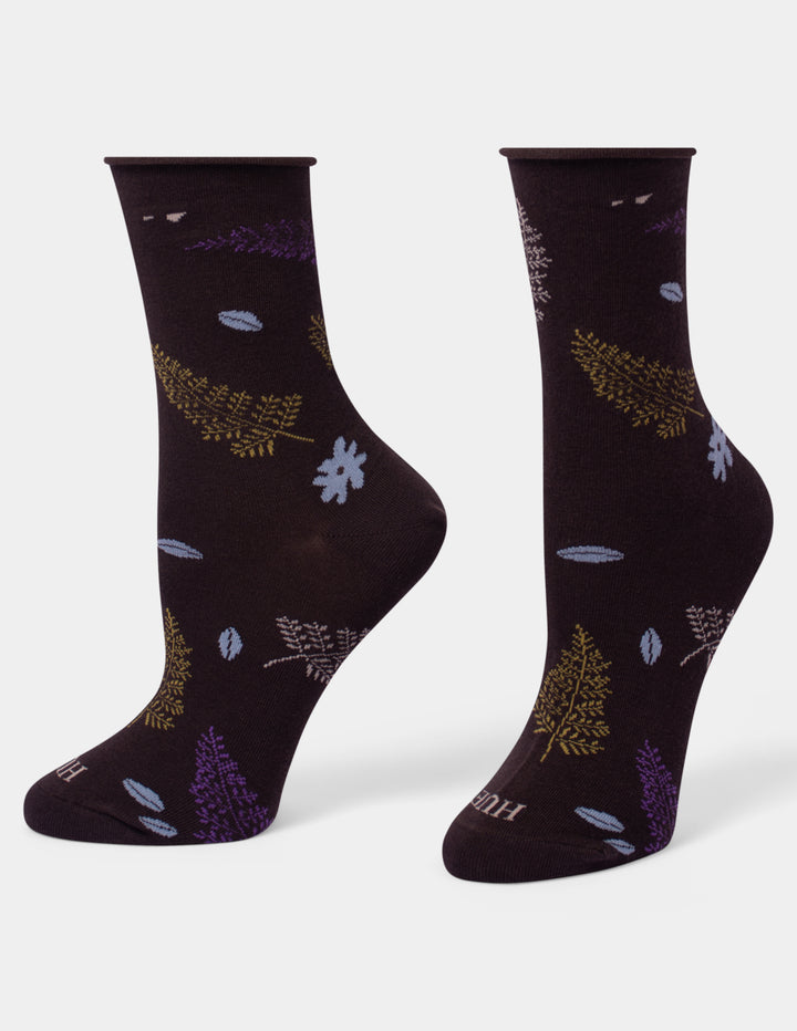 A pair of dark brown crew socks with a pattern of stylized leaves and ferns in purple, gold, and light blue, displayed on a clean white background.