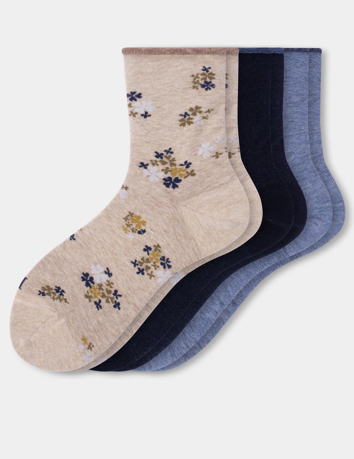 Three pairs of crew socks on a light gray background. The front pair is beige with a small floral pattern in navy and mustard yellow, and the back pairs are solid navy and heathered blue.