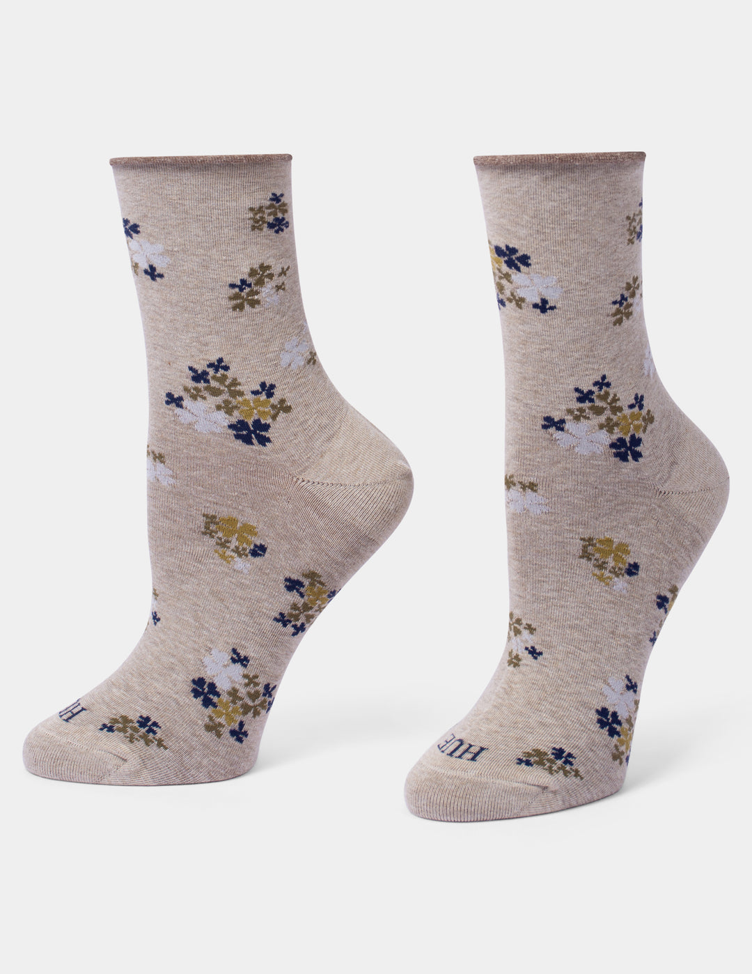 A pair of crew socks in a heathered beige color, decorated with a small floral pattern in navy blue, mustard yellow, and white.