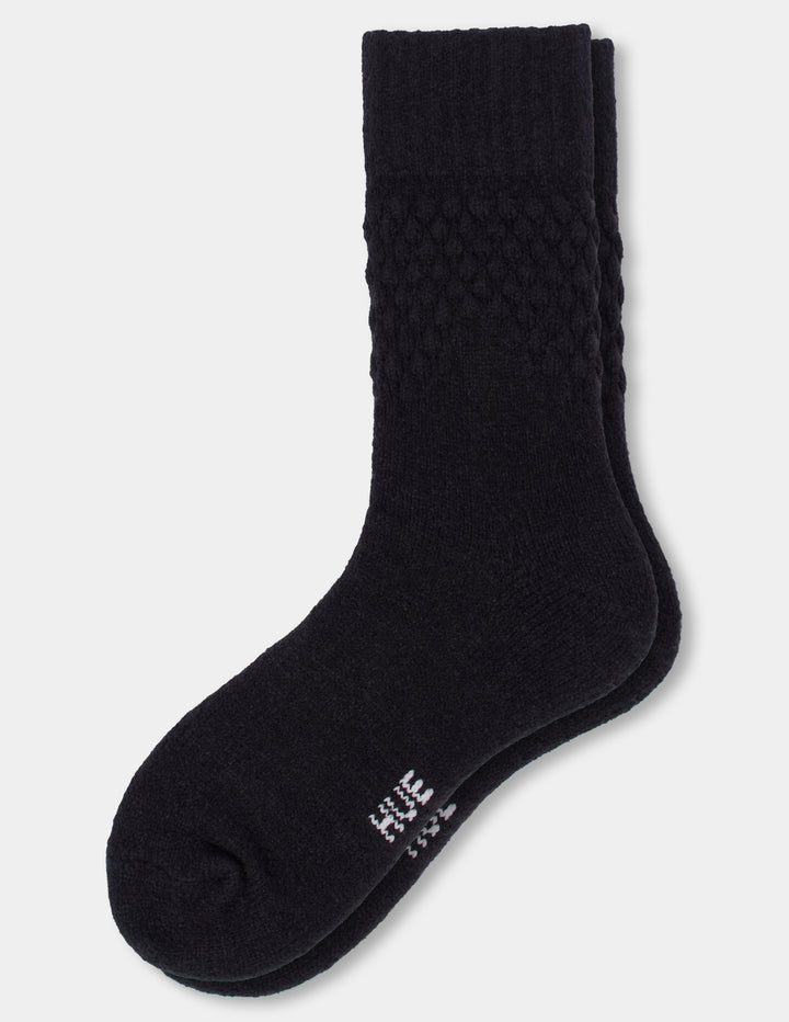 A pair of black textured crew socks against a light gray background.