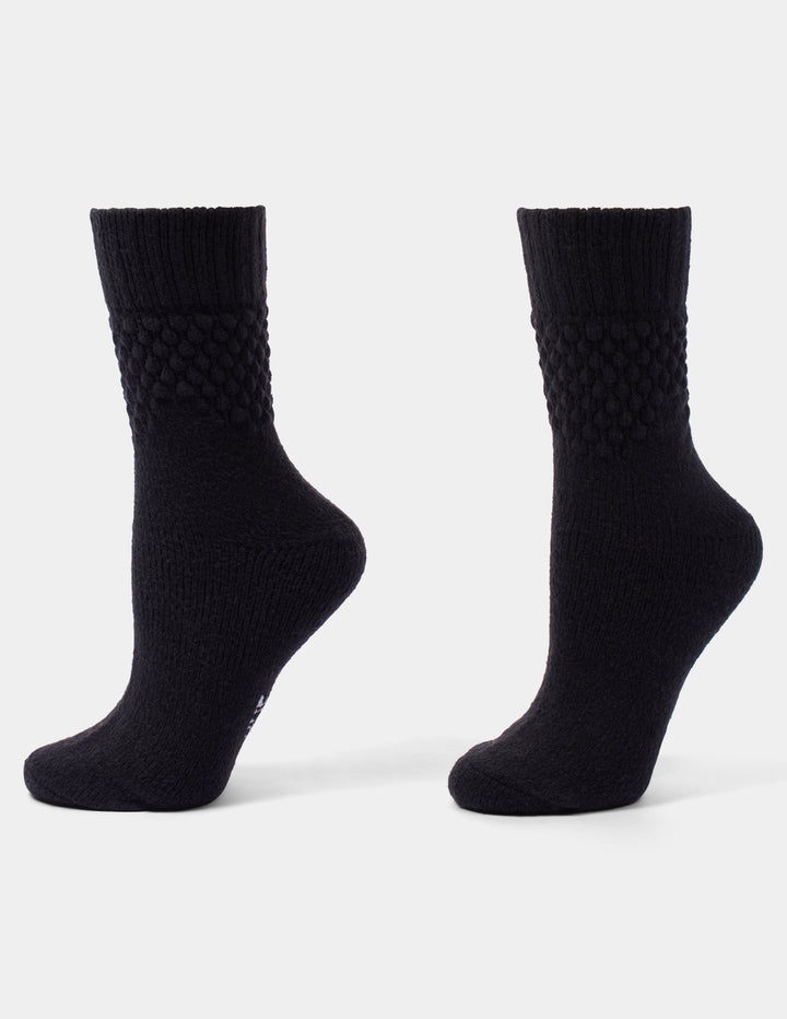 A pair of black crew socks with a textured, diamond-patterned ribbed cuff, shown from the side against a light gray background.