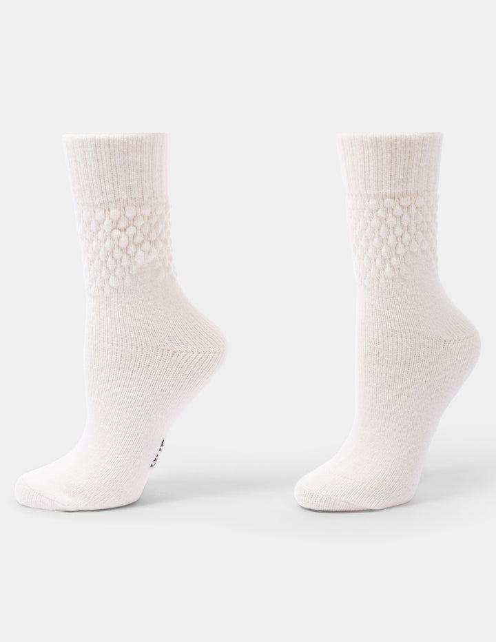 A pair of ivory textured crew socks against a light gray background.