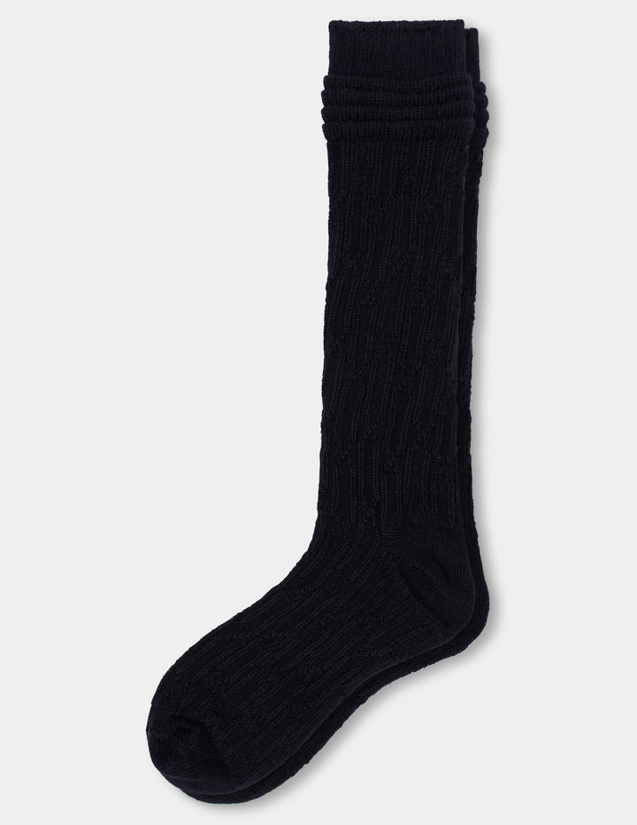 A pair of black cable knee socks against a light gray background. 