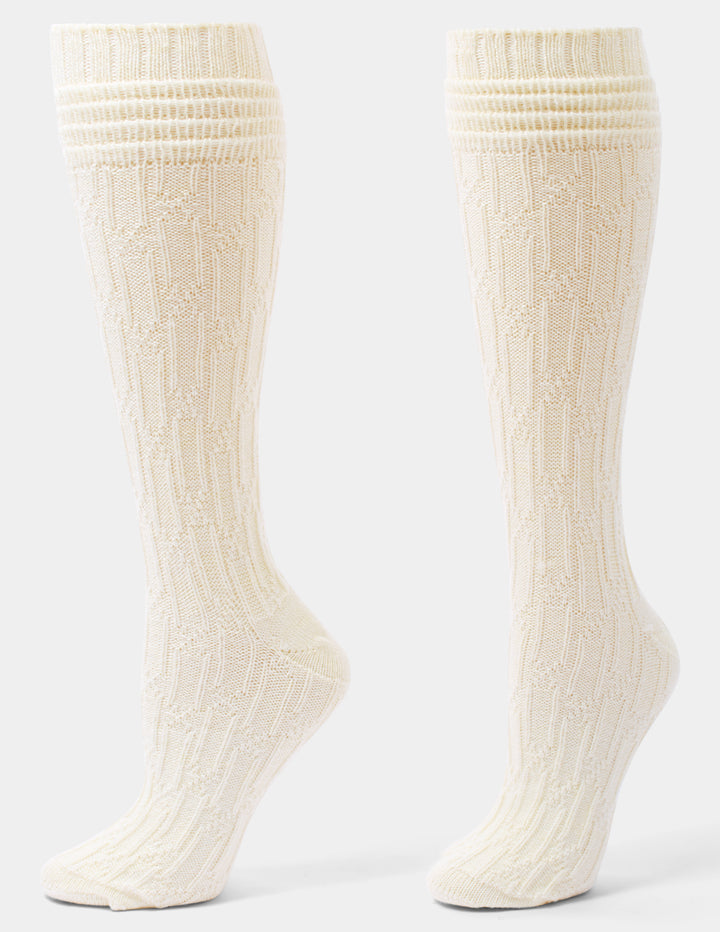 A pair of ivory cable knee socks against a light gray background. 