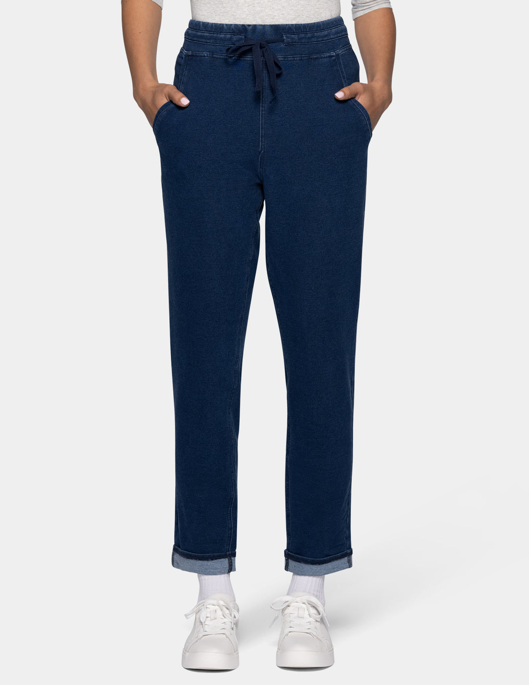 A person wearing dark blue joggers with a drawstring waist, shown from the waist down against a light gray background.