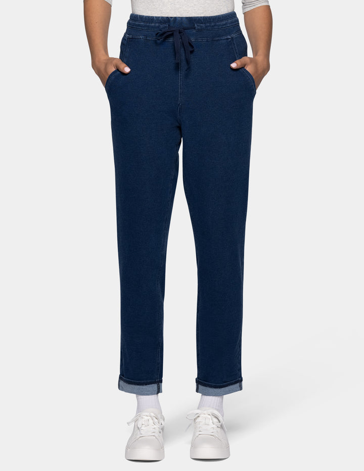 A person wearing dark blue joggers with a drawstring waist, shown from the waist down against a light gray background.