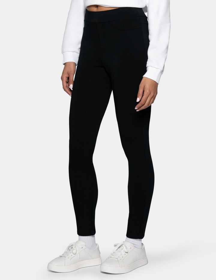 A model wearing black high-waisted leggings, a white cropped sweatshirt, white socks, and white sneakers, shown from the waist down against a light gray background.