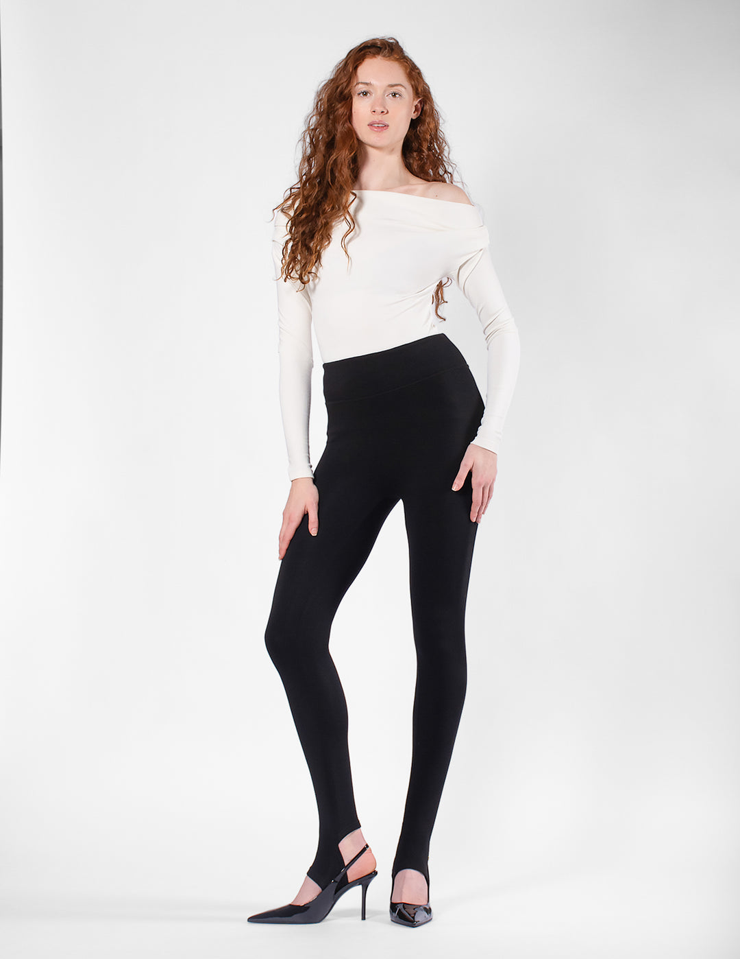 Woman wearing a white long-sleeve top and black leggings on a white background