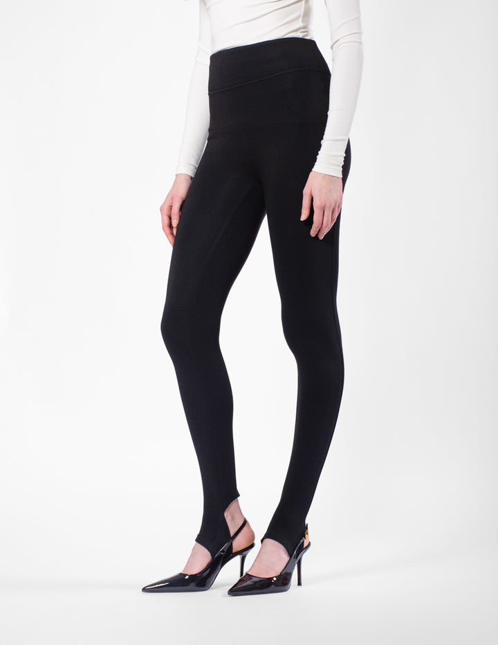 Person wearing black leggings and a white long-sleeve top on a white background
