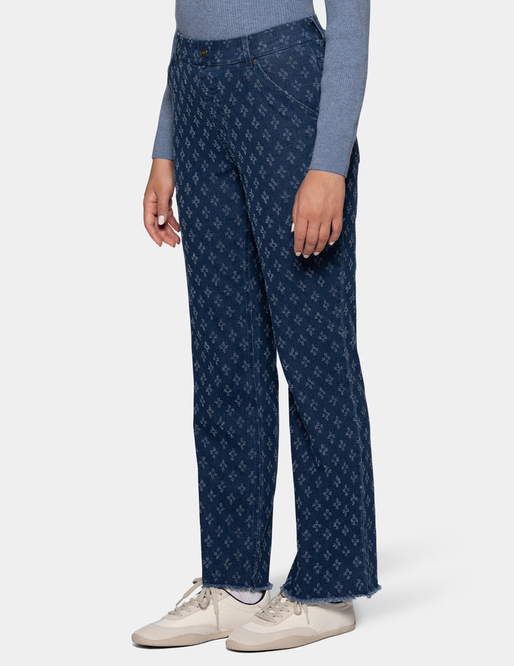 A sideview of a model wearing a heathered blue long-sleeve top, dark blue patterned pants, and off-white sneakers against a light gray background.