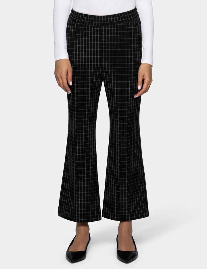 Black flare cropped pants with a white windowpane grid pattern, shown on a model wearing a white long-sleeve top and black flats against a light gray background.