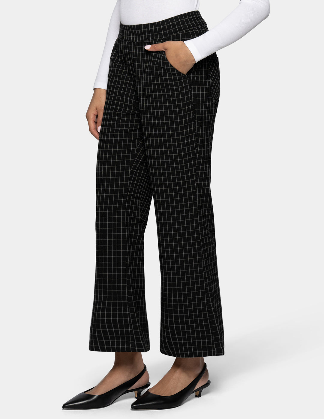 Black flare cropped pants with a white windowpane grid pattern, shown on a model wearing a white long-sleeve top and black kitten heels against a light gray background.
