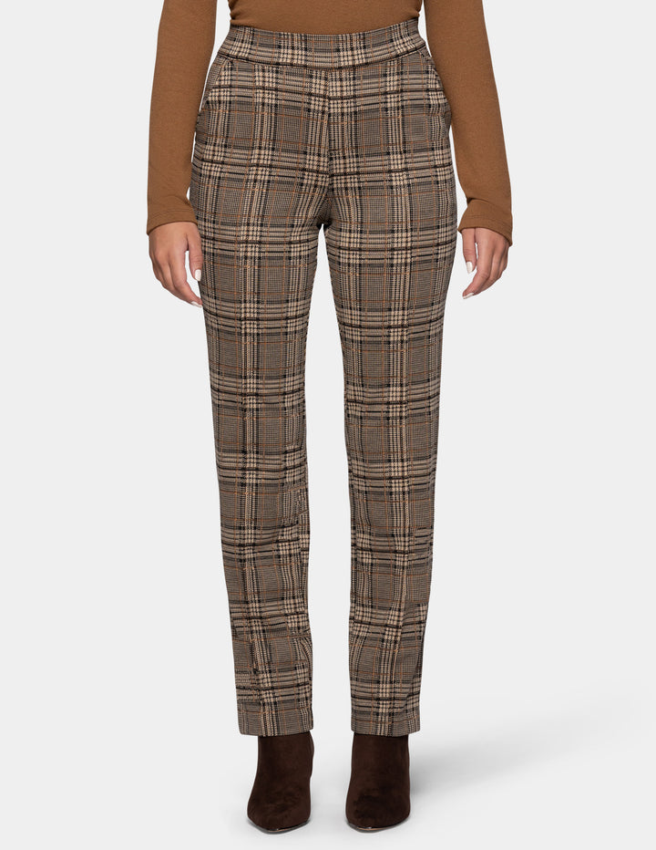 A model wearing brown plaid pants styled with a dark tan long sleeve top, and suede brown boots, against a plain gray studio background.