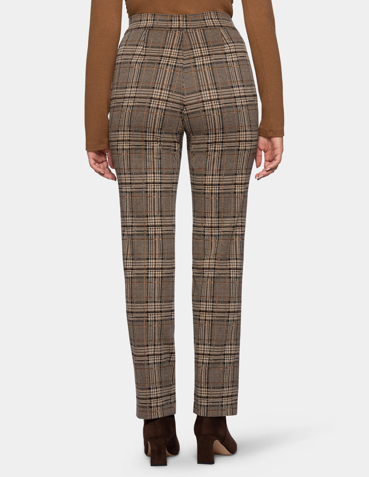 A backside view of a model wearing brown plaid pants styled with a dark tan long sleeve top, and suede brown boots, against a plain gray studio background.