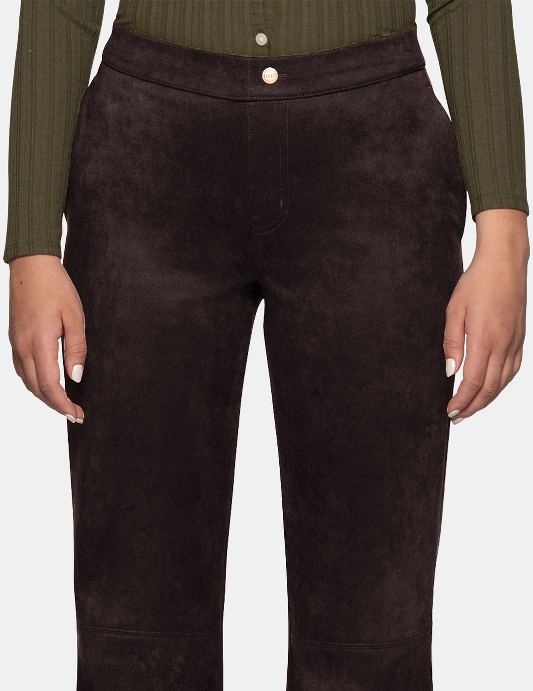 A model wearing dark brown suede flare pants paired with a long sleeve olive top, photographed against a light grey background.