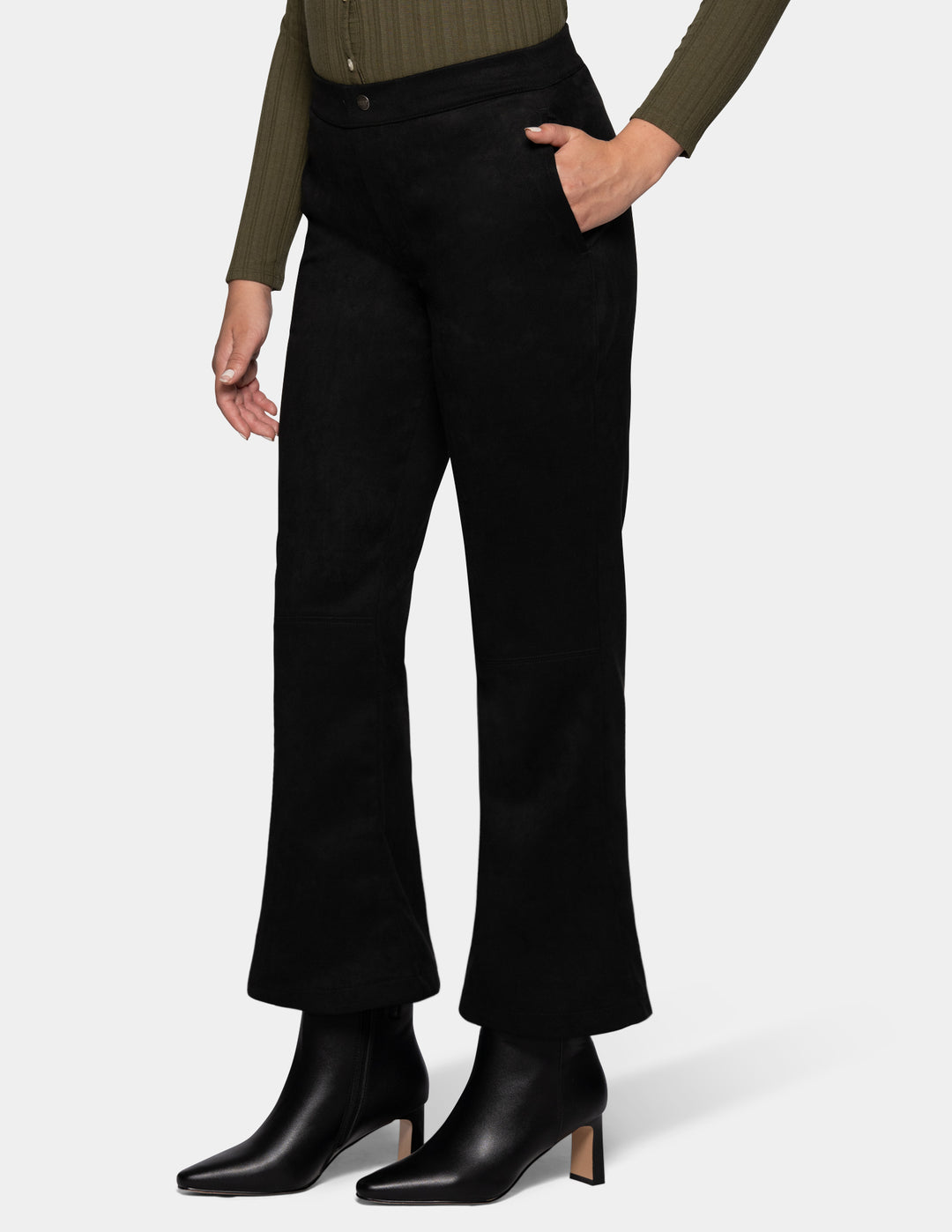 A sideview of a model wearing black flare pants, an olive green long sleeve top, and black booties, photographed against a light grey background.