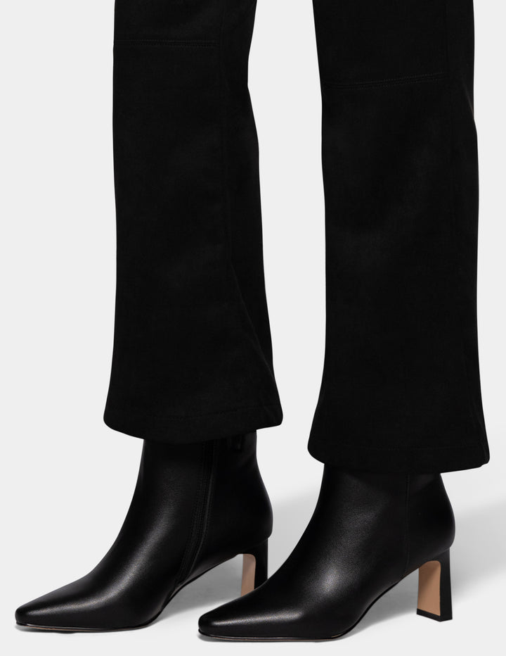 A close-up detailed view of a model wearing black flare pants and black booties.