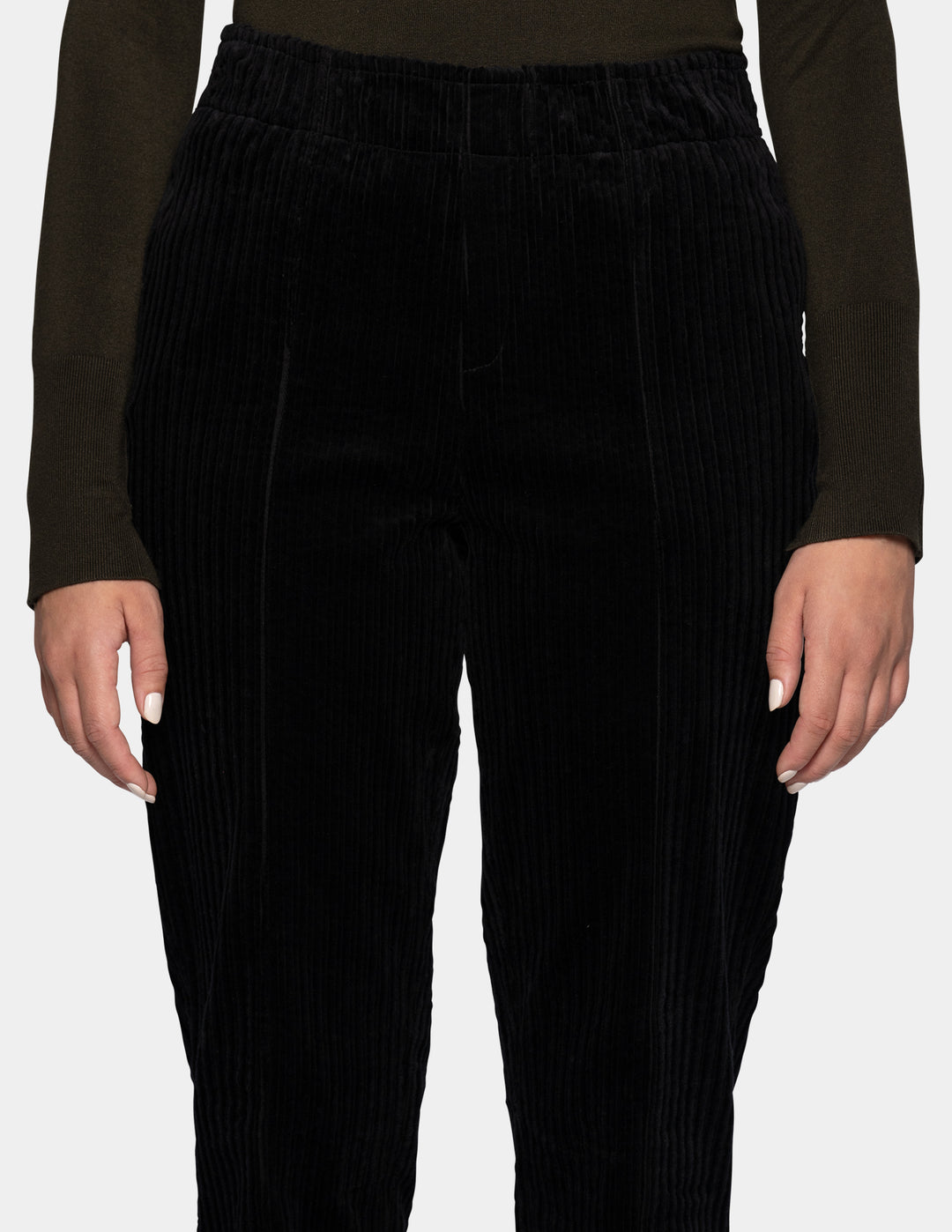 A model wearing black corduroy pants, and an olive green long sleeve top.