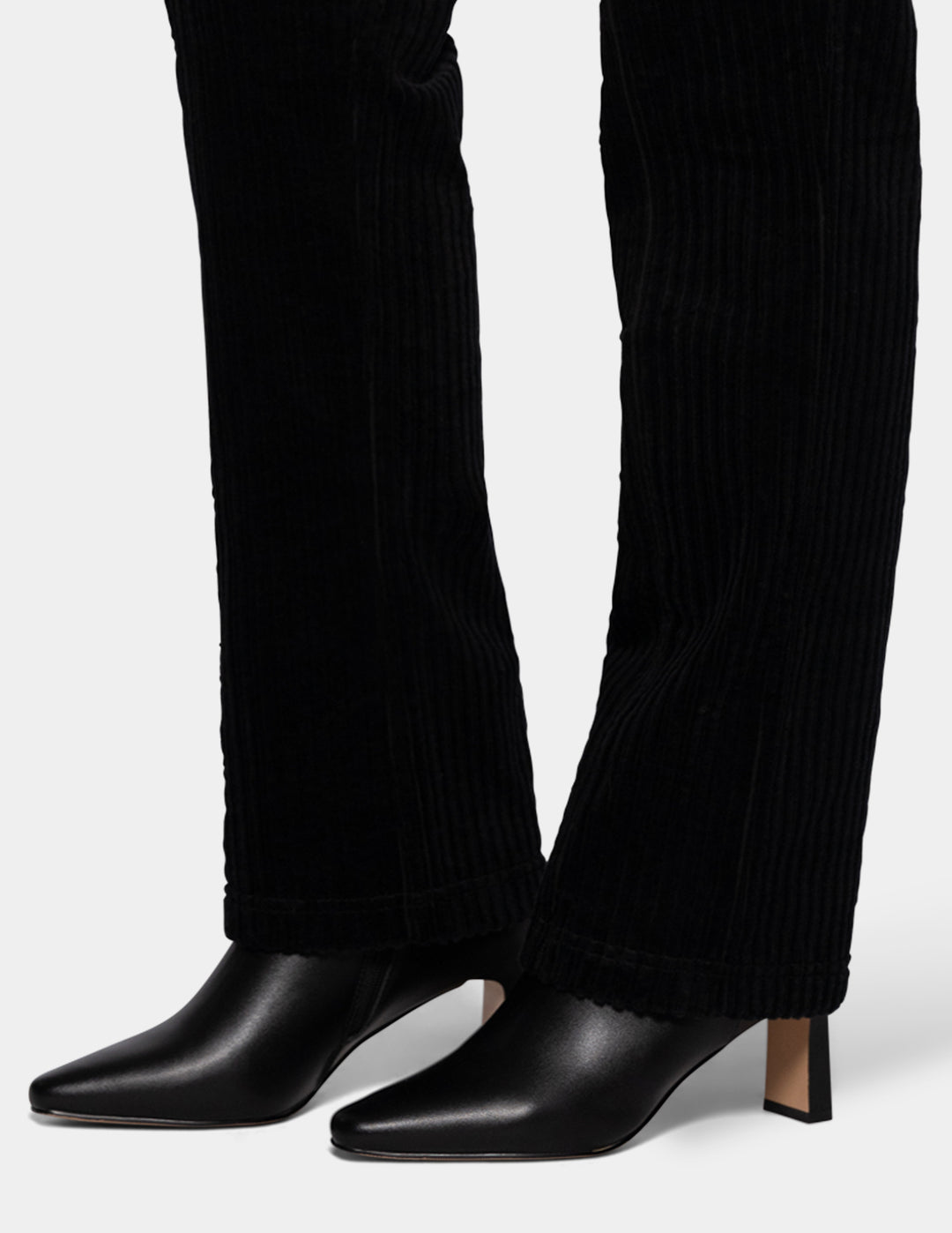 A model wearing black corduroy pants and black boots.