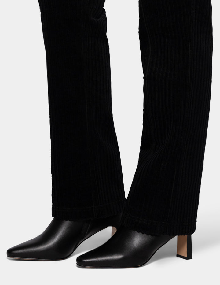 A model wearing black corduroy pants and black boots.
