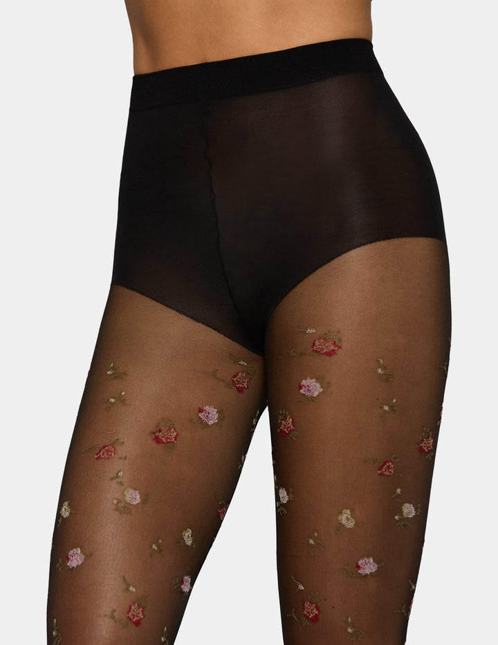 Black sheer high-waisted briefs paired with sheer black tights featuring a delicate pink and red floral pattern, shown on a model against a light gray background.
